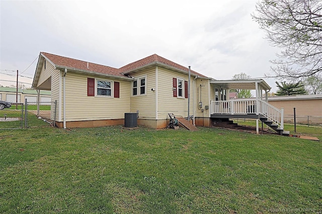 back of house with central air condition unit, fence, and a yard