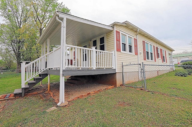 view of side of home featuring a gate, stairway, fence, a porch, and a yard