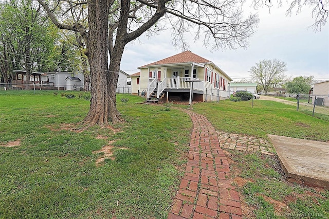rear view of property featuring a lawn, a porch, and fence