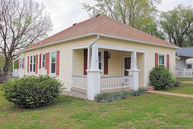 bungalow-style home with fence, a porch, and a front yard