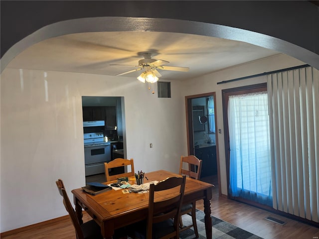 dining area featuring visible vents, a ceiling fan, wood finished floors, and arched walkways