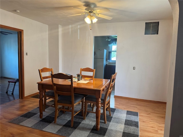 dining room with baseboards, a ceiling fan, wood finished floors, and arched walkways