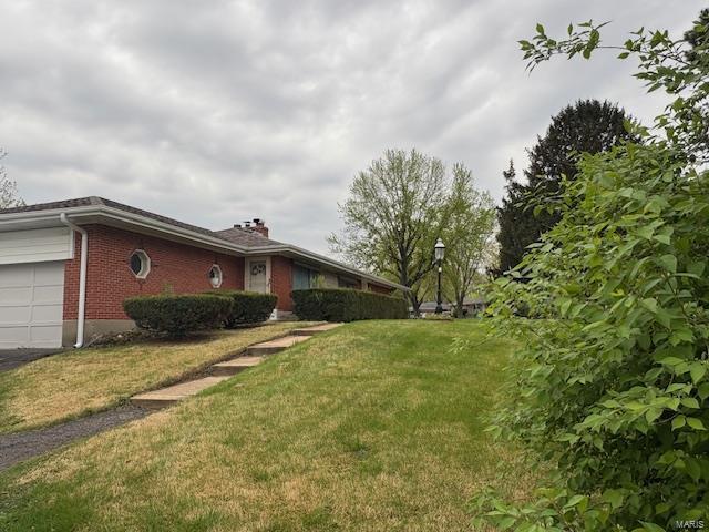 view of home's exterior with a lawn, brick siding, and a garage
