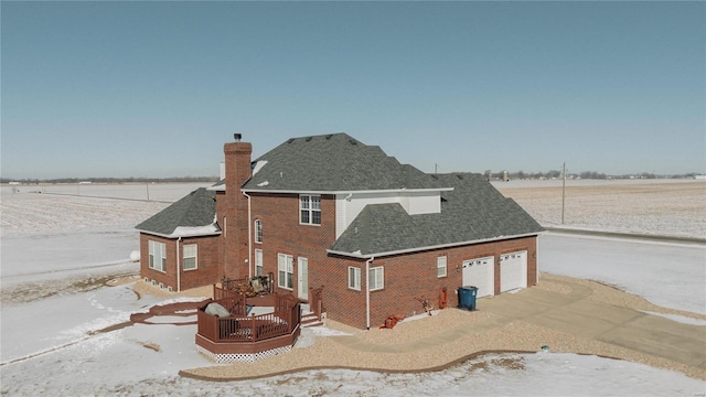 rear view of house featuring a chimney, brick siding, a wooden deck, roof with shingles, and an attached garage