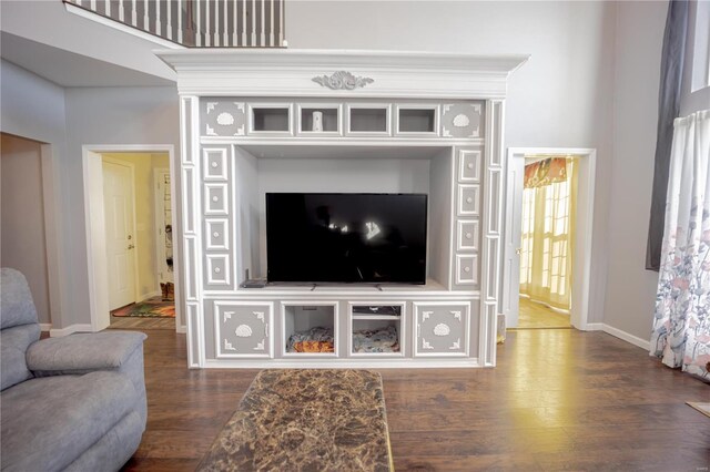 living room featuring dark wood-style flooring, a high ceiling, and baseboards