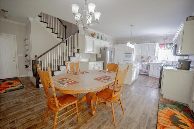 dining area featuring crown molding, beverage cooler, an inviting chandelier, wood finished floors, and stairs