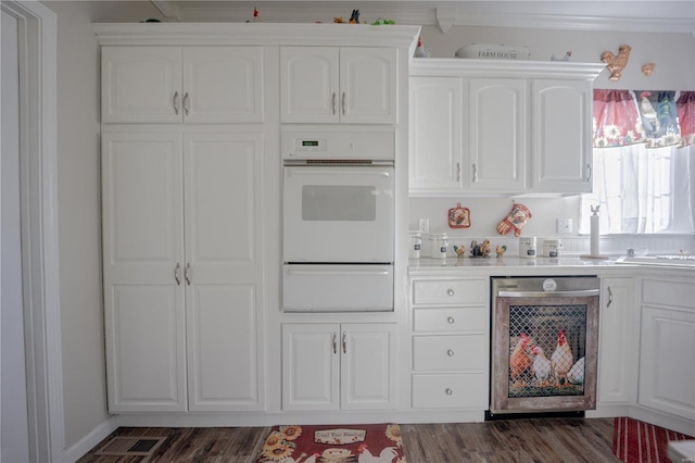 kitchen with a warming drawer, white oven, light countertops, dishwasher, and white cabinets