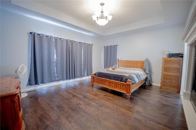 bedroom with wood finished floors, a chandelier, and a tray ceiling