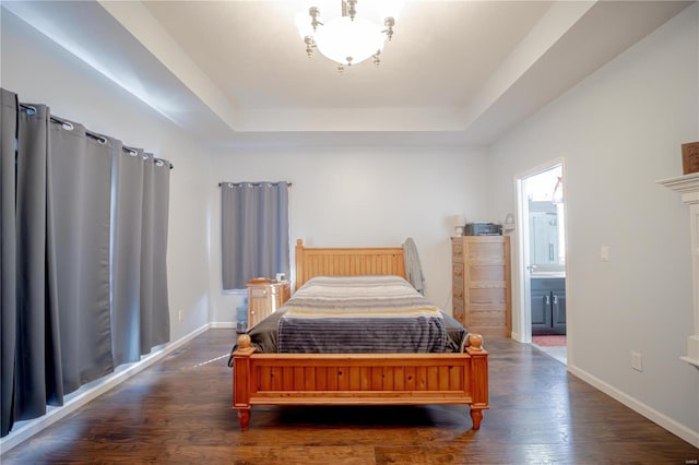 bedroom with baseboards, wood finished floors, and a tray ceiling