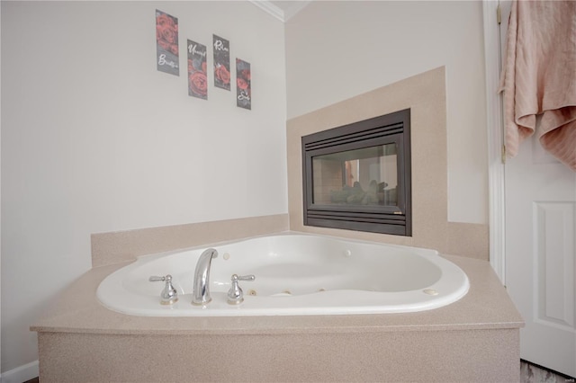bathroom with a glass covered fireplace, crown molding, and a jetted tub
