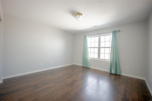 unfurnished room with visible vents, dark wood-style floors, and baseboards