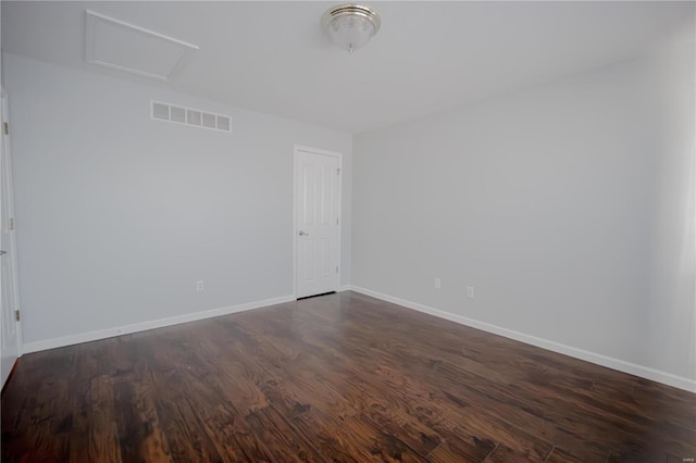 spare room featuring dark wood-style floors, visible vents, and baseboards
