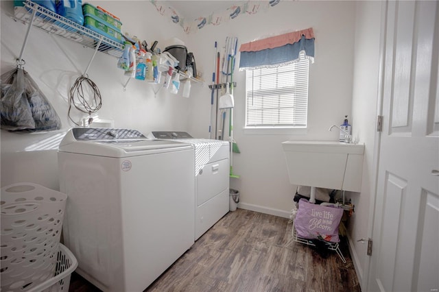 washroom with separate washer and dryer, wood finished floors, laundry area, and baseboards