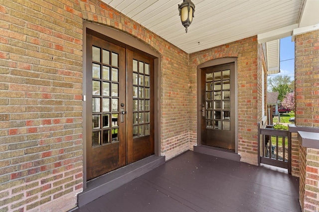 doorway to property with brick siding, french doors, and covered porch
