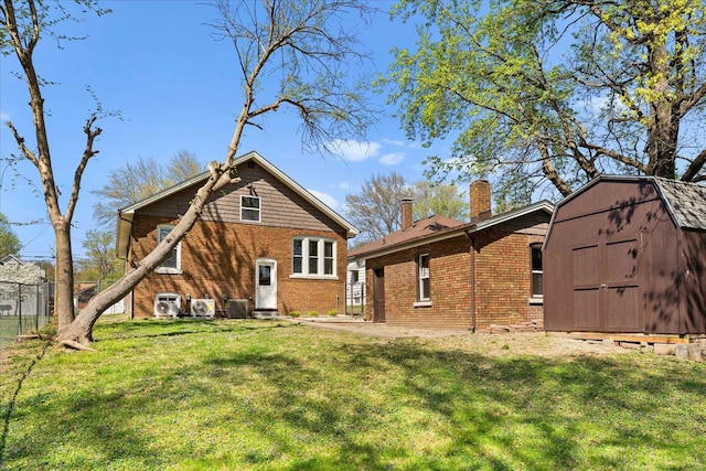 rear view of house with a chimney, an outdoor structure, brick siding, and a storage unit