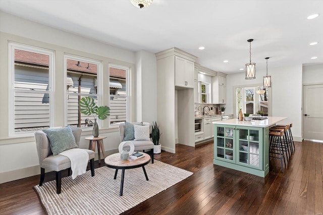 living area with baseboards, dark wood-style floors, and recessed lighting