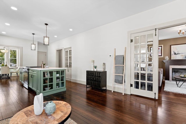 living area with a premium fireplace, recessed lighting, an inviting chandelier, and dark wood finished floors