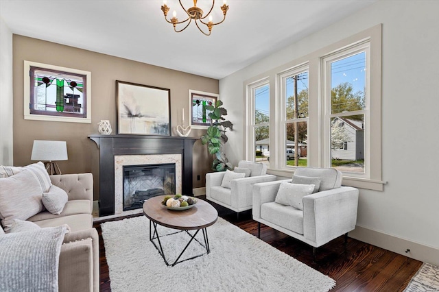 living room featuring a chandelier, a high end fireplace, baseboards, and dark wood-style flooring