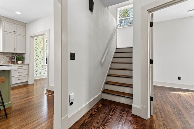 stairway with wood-type flooring, visible vents, baseboards, and recessed lighting
