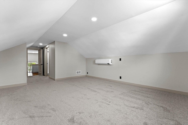additional living space with a wall unit AC, baseboards, recessed lighting, light colored carpet, and lofted ceiling
