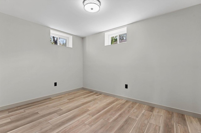 below grade area with a wealth of natural light, light wood-style floors, and baseboards