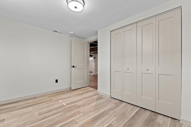 unfurnished bedroom featuring baseboards, a closet, visible vents, and light wood-type flooring