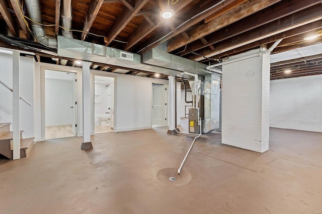 unfinished below grade area featuring stairway, heating unit, and visible vents