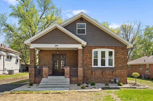 view of front of house featuring a porch, french doors, brick siding, and central AC unit