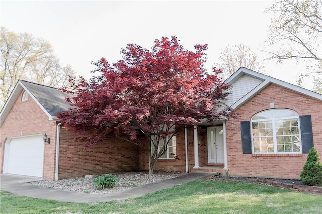 view of front of house featuring brick siding, a front yard, and a garage