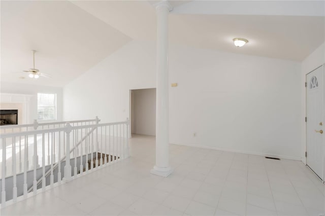 spare room featuring a fireplace, vaulted ceiling, a ceiling fan, and decorative columns