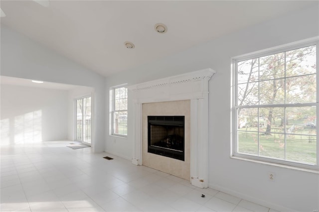 unfurnished living room featuring lofted ceiling, a healthy amount of sunlight, a tile fireplace, and visible vents
