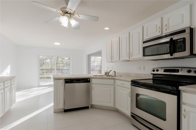 kitchen featuring a peninsula, a sink, white cabinetry, and appliances with stainless steel finishes