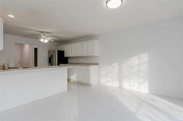 kitchen with a ceiling fan, a sink, light tile patterned flooring, stainless steel refrigerator with ice dispenser, and white cabinetry