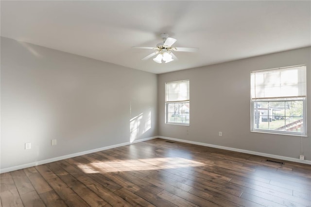 empty room with visible vents, a ceiling fan, baseboards, and dark wood-style flooring