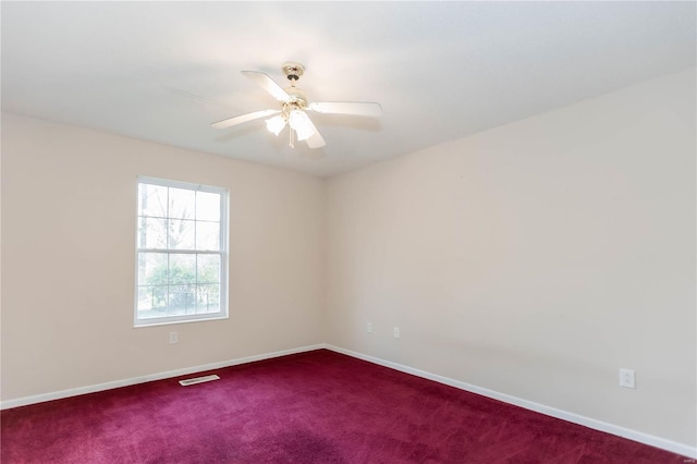 unfurnished room with dark carpet, visible vents, baseboards, and ceiling fan