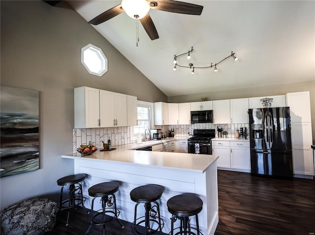 kitchen featuring a peninsula, a ceiling fan, light countertops, a breakfast bar, and black appliances