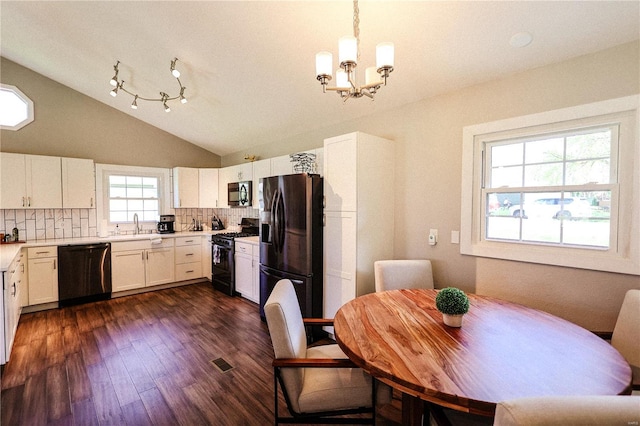 dining room featuring dark wood finished floors, an inviting chandelier, vaulted ceiling, and visible vents