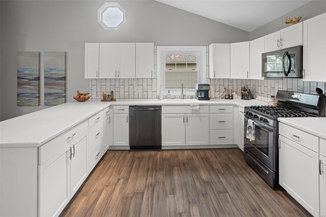 kitchen with dark wood finished floors, stainless steel appliances, vaulted ceiling, decorative backsplash, and a peninsula