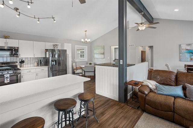 kitchen featuring lofted ceiling with beams, open floor plan, stainless steel appliances, and ceiling fan with notable chandelier