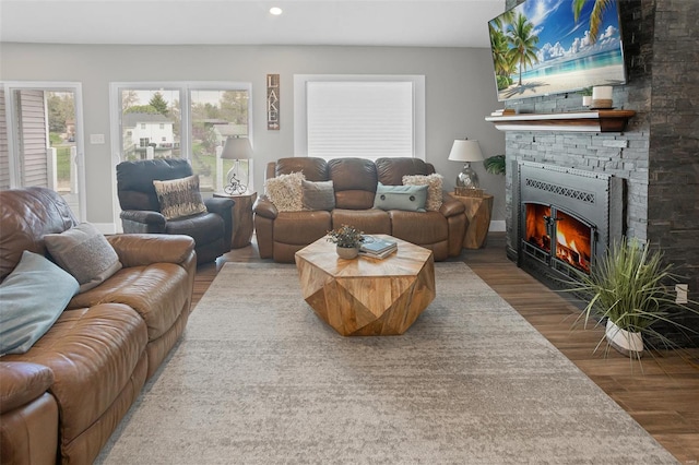 living area with a stone fireplace, wood finished floors, and recessed lighting