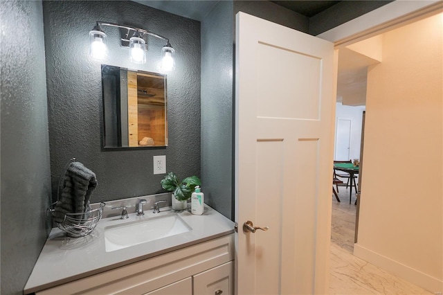 bathroom with marble finish floor, a textured wall, and vanity