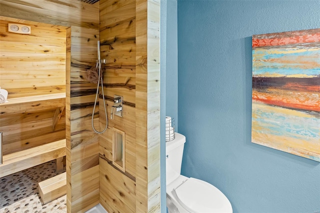 full bath with a tile shower, a textured wall, toilet, and a sauna