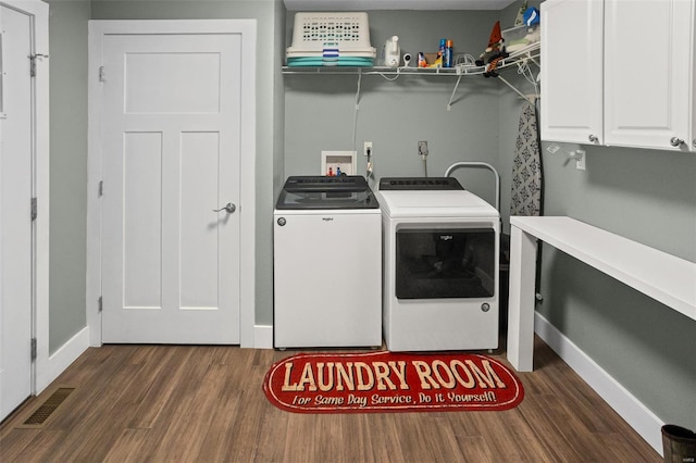 clothes washing area with dark wood finished floors, baseboards, visible vents, separate washer and dryer, and cabinet space
