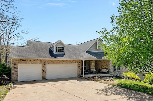 view of front facade with a shingled roof, driveway, covered porch, brick siding, and a garage