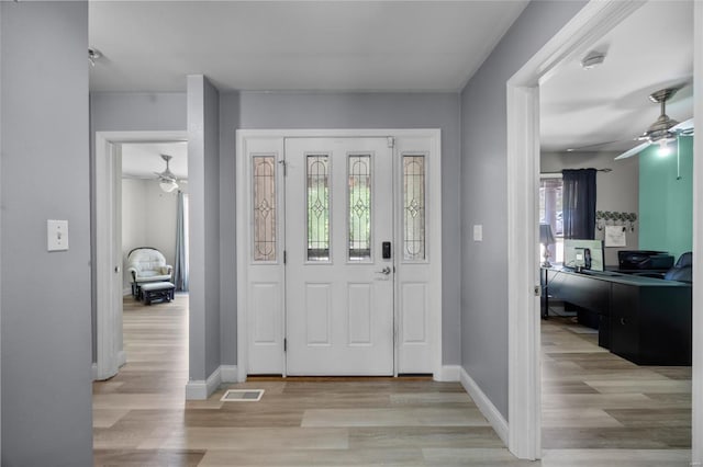 foyer with light wood-type flooring, baseboards, ceiling fan, and visible vents