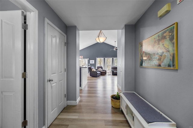 hall with lofted ceiling, light wood-style flooring, and baseboards