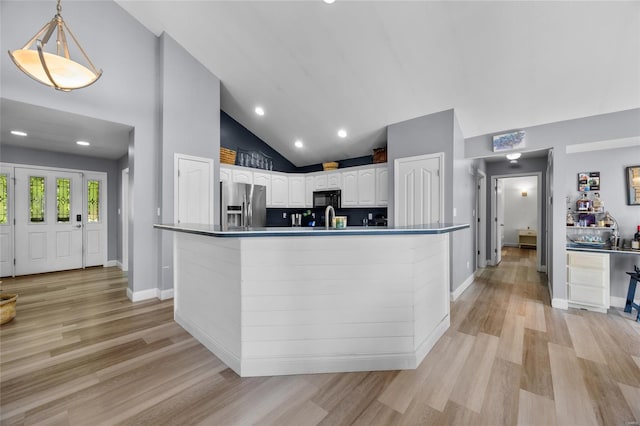 kitchen featuring light wood finished floors, white cabinetry, stainless steel fridge with ice dispenser, black microwave, and high vaulted ceiling