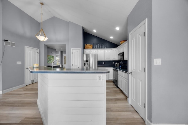 kitchen featuring visible vents, a kitchen island with sink, black appliances, high vaulted ceiling, and white cabinetry