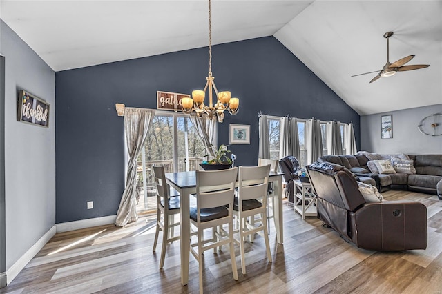 dining room featuring ceiling fan with notable chandelier, wood finished floors, a wealth of natural light, and high vaulted ceiling
