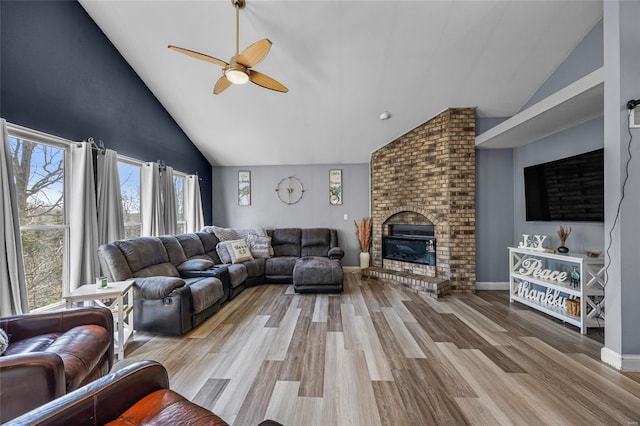 living area with high vaulted ceiling, ceiling fan, wood finished floors, and a fireplace